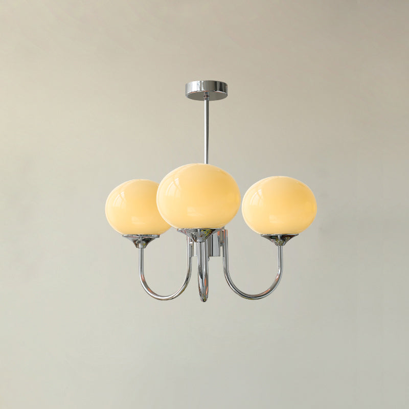 De LichtWolk Marshmallow Luchter met drie amberkleurige glazen bollen en een goudkleurige armatuur, elegant gemonteerd tegen een klassieke plafondrozet. Deze luxe hanglamp straalt een warme gloed uit, perfect voor sfeervolle verlichting in een stijlvolle kamer.